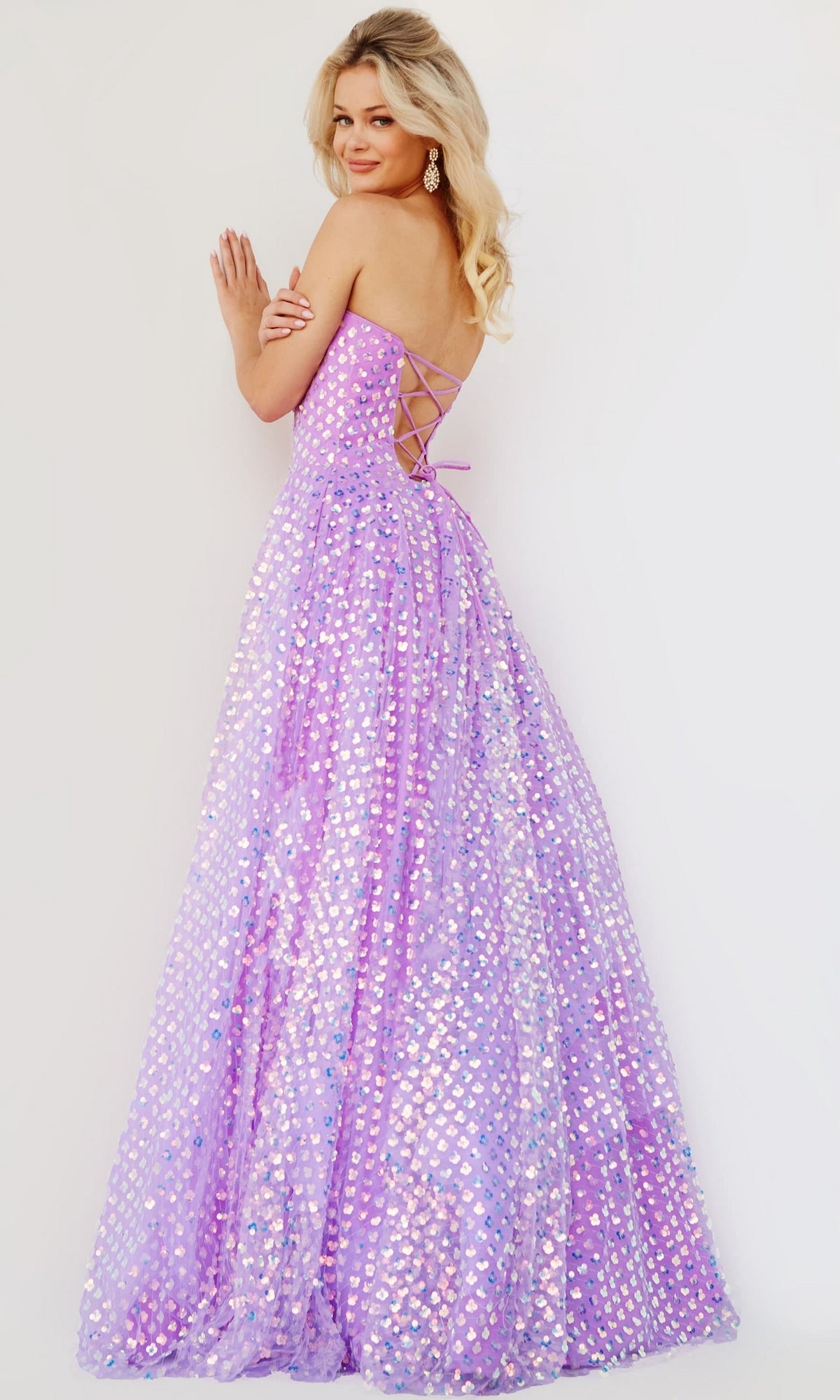 Woman wears the Jovani Strapless Sweetheart Long Prom Dress 08605, featuring iridescent sequins and a lace-up back, styled elegantly against a plain light background.